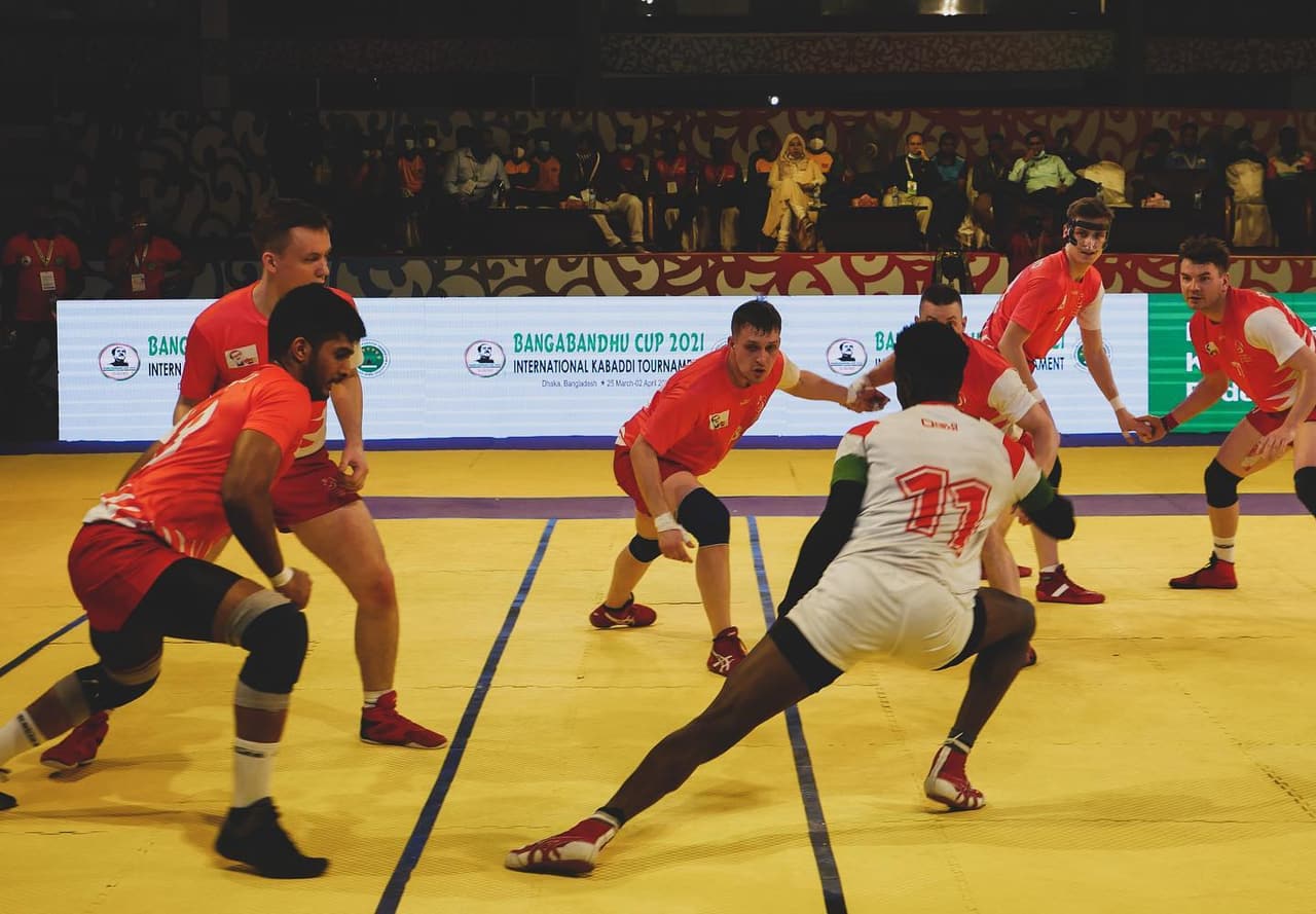 A Kenya raider in white stretches away from a red-shirted defence at the 2021 Bangabandhu Cup in Dhaka.