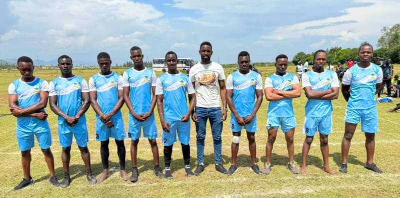 A kabaddi squad in light-blue kit lined up on a grass field.